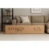 Cardboard box by beige sofa in living room